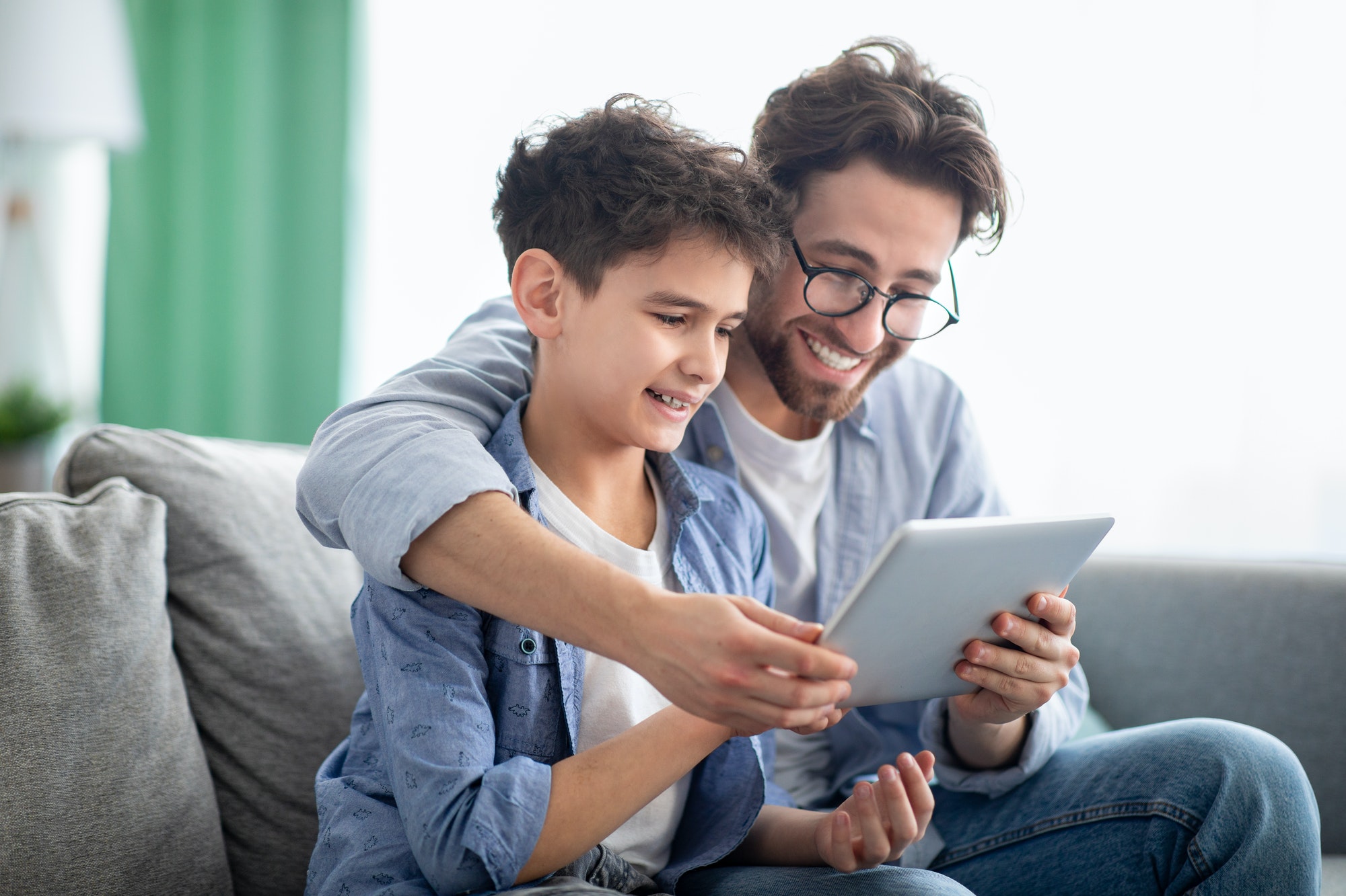 weekend family leisure happy father and son using tablet computer browsing internet online at home